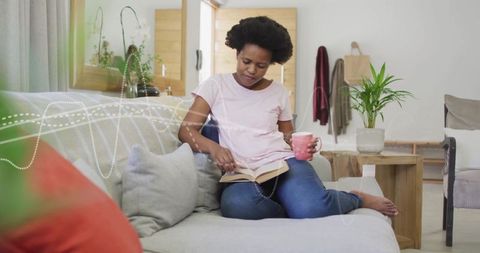 Woman Enjoying Coffee While Relaxing and Reading Book at Home