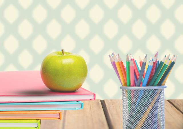Colorful books stacked on a wooden plank with a green apple and a pen holder filled with multicolored pencils. Ideal for educational websites, school materials advertisements, back-to-school campaigns, stationery product promotions, and classroom decoration inspirations.