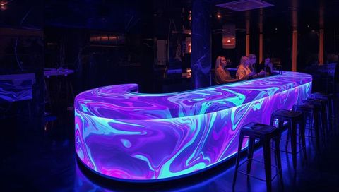 Glowing Marble-Effect LED Bar Counter in Neon Lounge with Casual Patrons