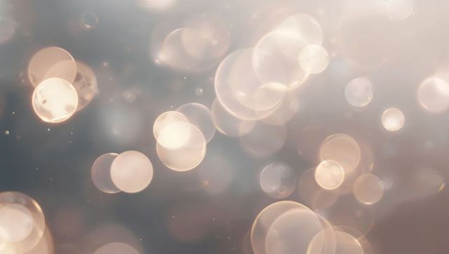 Floating glowing bokeh orbs creating dreamy abstract light background with soft golden glow