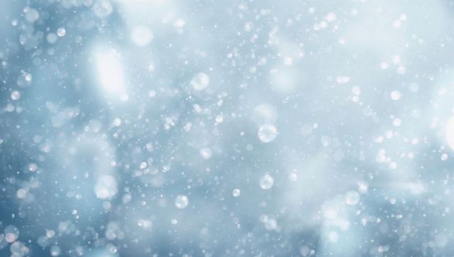 Drifting teal winter bokeh with falling snow and soft light particles