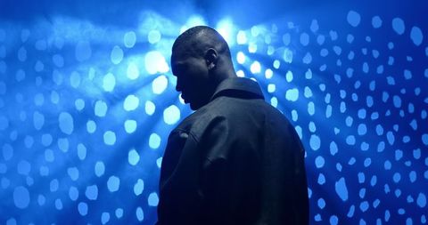 Man on stage with blue lighting and hazy atmosphere