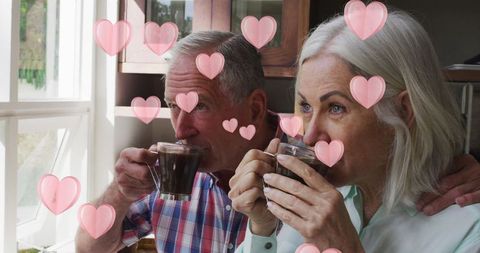 Senior Couple Enjoying Coffee with Digital Heart Icons