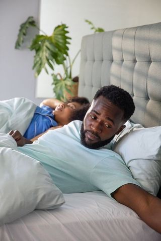 Couple Lying in Bed with Contemplative Expressions Modern Bedroom