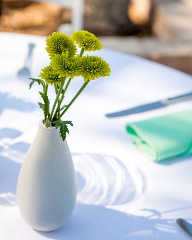 Vibrant green flowers design in elegant white vase on dining table