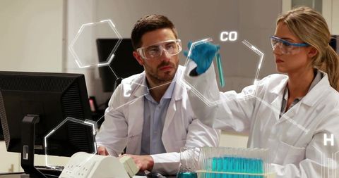Scientists Holding Blue Test Tube While Collaborating on Chemical Analysis in Laboratory