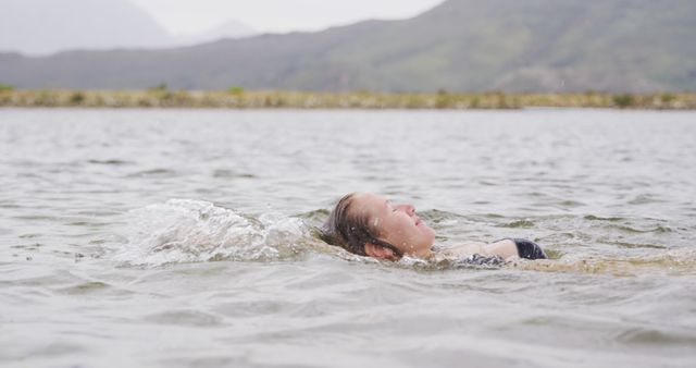 Woman Swimming on her Back in Natural Lake Surrounded by Mountains - Download Free Stock Images Pikwizard.com