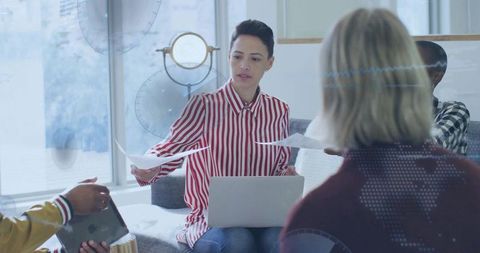 Businesswoman passing documents during informal team meeting in modern coworking space