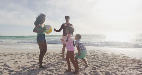 Family Enjoying Day at Beach Playing Ball Together