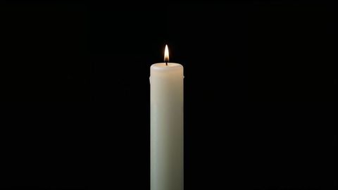 Flickering white candle against dark background for condolences