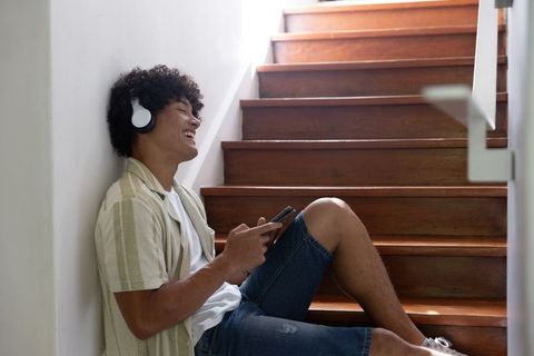 Youth enjoying music on headphones relaxing on wooden steps