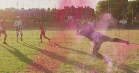 Diving Goalkeeper Stretching for Aerial Save with Lens Flare on Outdoor Soccer Field