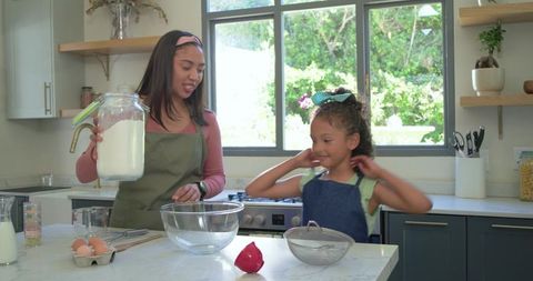 Mother and daughter baking together on sunlit kitchen counter for family moments