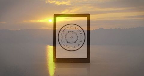 Tablet Displaying Digital Interface Against Sunset Over Tranquil Lake