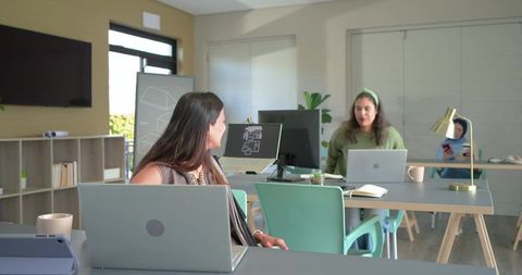 Asian Indian woman collaborating with coworkers in modern open-plan office workspace