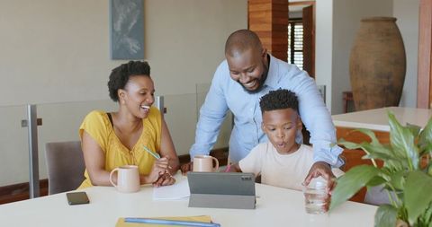 African American Family Assisting Son with Tablet for Remote Learning in Bright Open Home