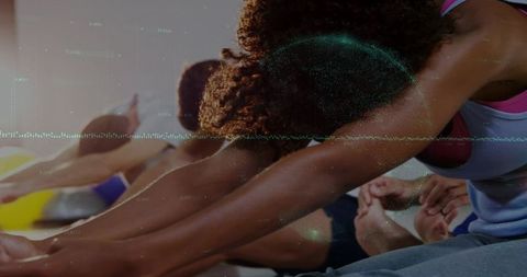 Curly-haired woman stretching forward in group fitness class with diagonal composition