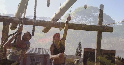 Athletic duo conquering outdoor rope obstacle challenge