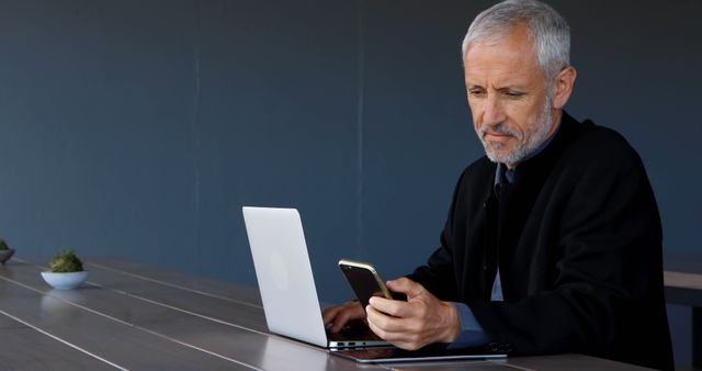 Senior Man Working on Laptop and Phone in Modern Office - Download Free Stock Images Pikwizard.com