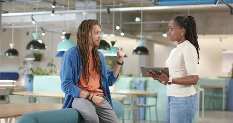 African American Coworkers Discussing Project on Tablet in Modern Open-Plan Office Lounge