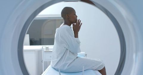 Contemplative african woman preparing for mri scan while sitting inside scanner gantry in hospital g
