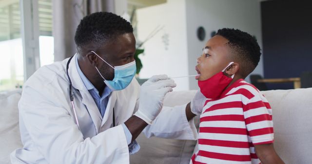 A healthcare professional wearing a face mask and gloves is administering a test swab to a young boy in a striped shirt. The focus is on healthcare and patient safety during a medical examination. This image is suitable for use in articles related to healthcare, pediatric care, medical testing at home, health awareness campaigns, or emphasizing the importance of safety protocols in medical practices.
