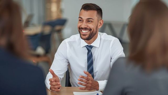 Smiling businessman gesturing during team meeting, confident leader presenting ideas