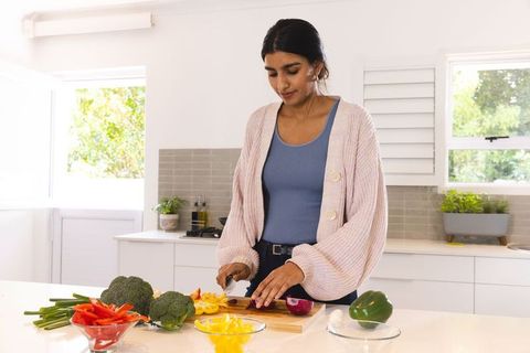 Woman Preparing Fresh Vegetables for Healthy Meal in Bright Kitchen
