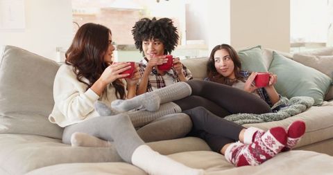 Diverse Female Friends Relaxing on Couch with Hot Beverages