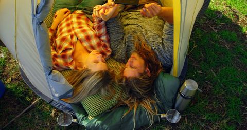 Relaxed Couple Lounging in Tent with Mobile Phone
