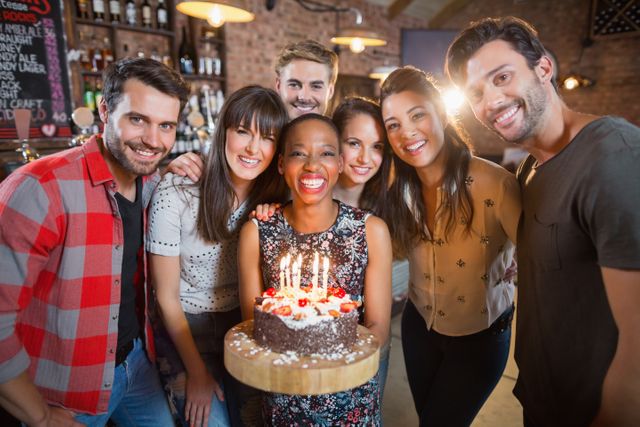Portrait of happy friends holding birthday cake in restaurant