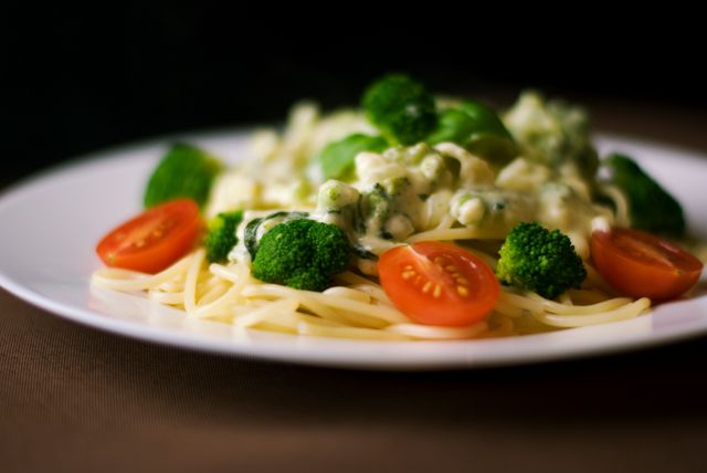 vegetarian pasta dish is featuring spaghetti, creamy broccoli sauce, and cherry tomatoes garnishing. Appeals to Italian cuisine enthusiasts, suitable for food blogs, recipe websites, restaurant menus, vegetarian dining promotions. Provides a visual of appetizing and healthy meal options.