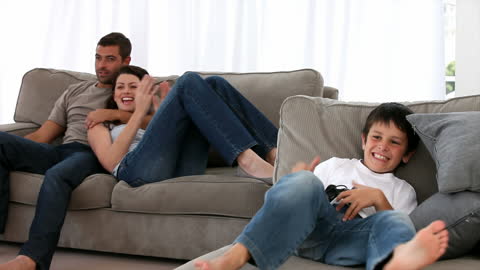 Family Enjoying Watching Boy Play Video Games at Home