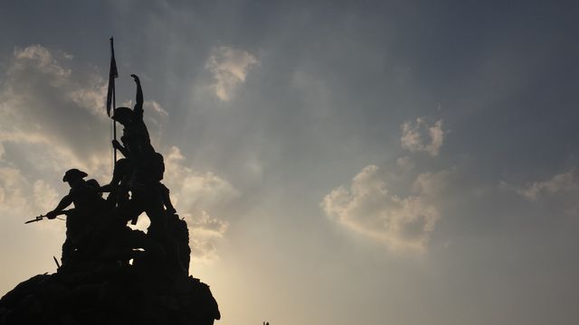 Suitable for historical and patriotic themes, this image showcases a dramatic silhouette of a soldier's monument against a sunset sky. The intense backlighting emphasizes the heroism and readiness of the soldiers frozen in time. Ideal for educational materials, history presentations, or commemorative displays, conveying themes of patriotism, sacrifice, and bravery.