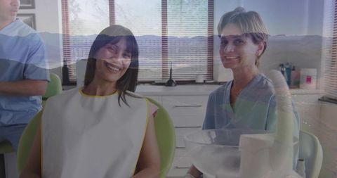 Smiling patient sitting in green dental chair with dental hygienist smiling and team working