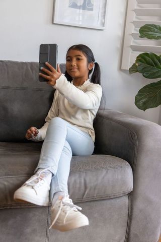 Young asian girl taking selfie on gray couch in cozy modern living room