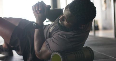 Man using foam roller for muscle recovery in modern gym