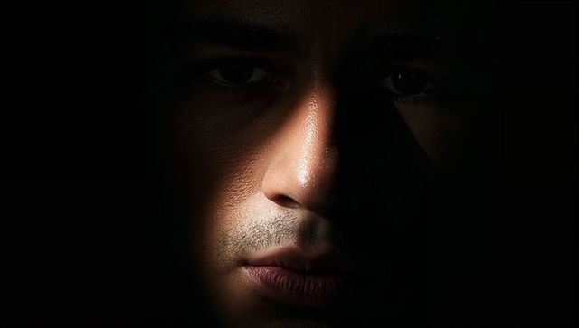 Low-key Closeup Male Face with Narrow Warm Beam Creating Dramatic Chiaroscuro Portrait