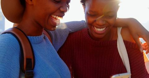 African american twins joyfully sharing mobile moment in cityscape