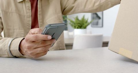 Man tracking package delivery using smartphone in modern living room