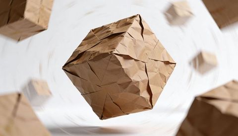 Floating crumpled kraft paper cube rotating with motion blur, folded origami geometric