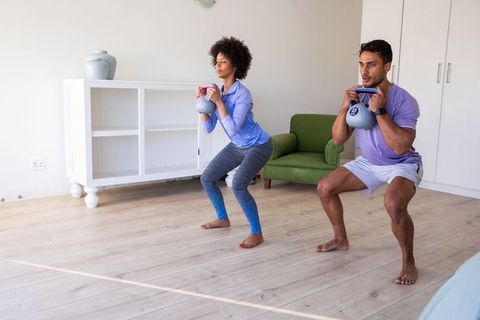 Diverse Couple Performing Kettlebell Squats in Modern Living Room
