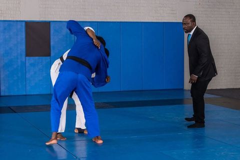 Instructor supervising judo training on blue mats in dojo