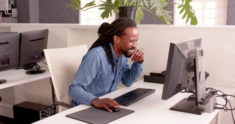 Joyful Man Celebrating Success at Desk in Modern Office