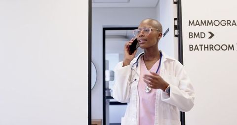 Female clinician talking on phone in mammography corridor with pink scrubs and stethoscope