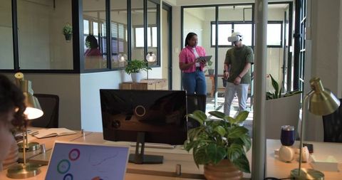 Diverse team collaborating with vr headset and tablet in modern open-plan office