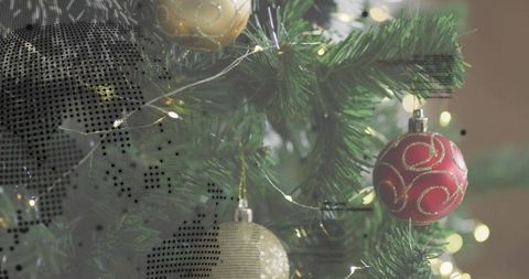 Cozy christmas tree close-up with red bauble, gold ornaments and warm fairy lights