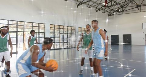 Indoor basketball team practicing defensive drill with crouching player protecting ball