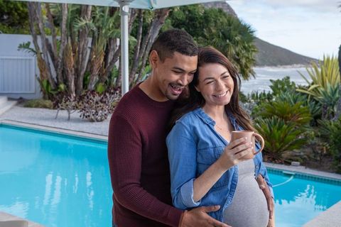 Diverse Couple Embracing by Beachside Pool with Coffee Mug