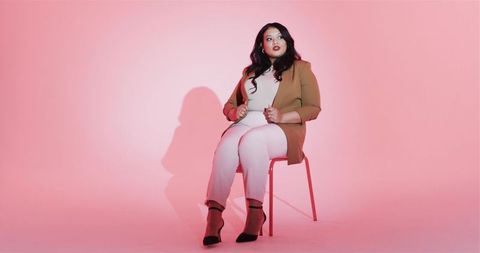 Confident Fashionable Woman Sitting in Modern Studio